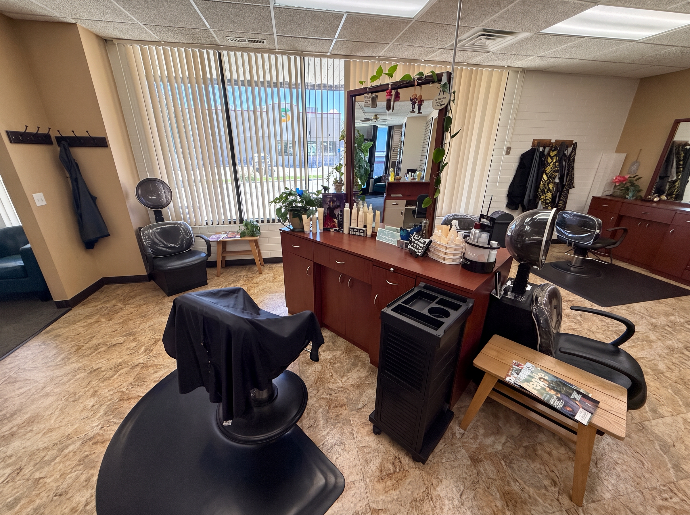 A stylist workspace at Clipped Accent with warm wood cabinetry, mirror, and salon equipment beside a bright window